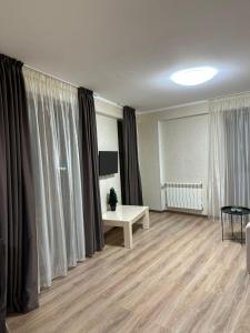 ein Wohnzimmer mit Vorhängen, einem Tisch und einem TV in der Unterkunft Orbi Palace Bakuriani 101 in Bakuriani