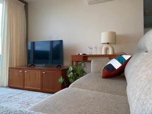 een slaapkamer met een bed en een tv op een houten kast bij Myrtus - House with sea view and garden in Funchal