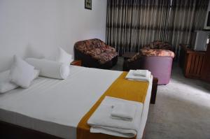 a bedroom with a large bed with two chairs and towels at Trinco Rest House in Trincomalee