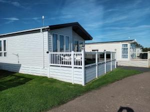 a white house with a fence in front of it at Beautiful 4 Berth Lodge With Free Wifi At Pakefield Holiday Park Ref 68019cr in Lowestoft