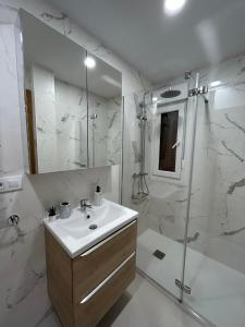 y baño blanco con lavabo y ducha. en Apartamentos Sudestada, en Logroño