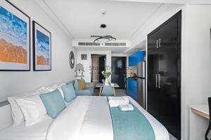 a bedroom with a large white bed with blue accents at StoneTree - New Studio in JLT in Dubai