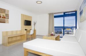 ein Schlafzimmer mit Bett, Schreibtisch und Fenster in der Unterkunft Ereza Apartamentos Los Hibiscos - Adults Only in Puerto del Carmen