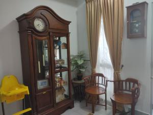 a grandfather clock and two chairs in a room at Hulu Yam Musliim Homestay in Batang Kali