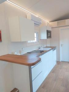 uma cozinha com armários brancos e um balcão de madeira em Tiny House Paradies em Wustermark