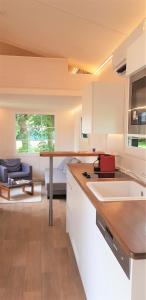 uma cozinha com armários brancos e uma sala de estar em Tiny House Paradies em Wustermark
