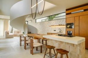 an open kitchen with a large island with stools at Lyvin Bingin Villas in Uluwatu