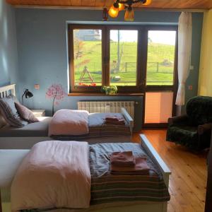 a bedroom with two beds and a window and a couch at Agroturystyka Zagroda Miłkowskie in Słopnice