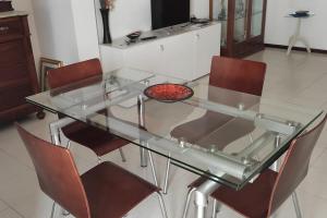 a glass dining table with four chairs and a television at Lella's Home in Quartu SantʼElena