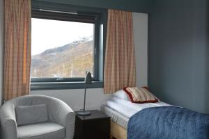 a bedroom with a bed and a chair and a window at Vatnahalsen Høyfjellshotell in Myrdal