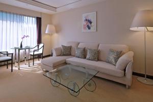 un soggiorno con divano e tavolo in vetro di Prudential Hotel a Hong Kong