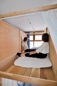 twee vrouwen op een bed in een kamer bij Guesthouse Imaichi ゲストハウス今市マチナカ in Nikko