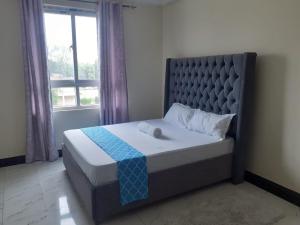 ein Bett in einem Schlafzimmer mit einem großen Fenster in der Unterkunft TWO BEDROOM APARTMENT BAMBURI Mombasa in Mombasa