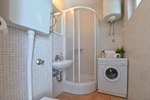 ein Badezimmer mit einer Waschmaschine und einem Waschbecken in der Unterkunft Apartment Adela I with Terrace in Novalja