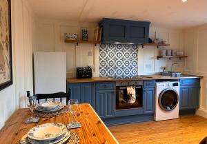a kitchen with blue cabinets and a table with a washer at Octon Cottages Luxury 1 and 2 Bedroom cottages 1 mile from Taunton centre in Taunton