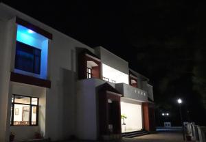 a night view of a white building with blue lights at Pine Hideout in Kathua