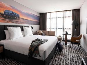 Novotel Perth Murray Street في بيرث: غرفة الفندق بسرير كبير ومكتب