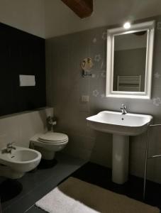 a bathroom with a sink and a toilet and a mirror at De' Pepoli Rooms & Apartments in Bologna