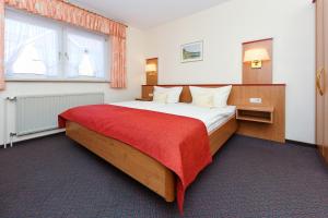 a bedroom with a large bed with a red blanket at Pension Nordkap in Bensersiel