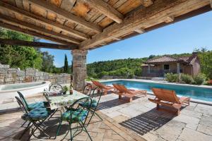 a patio with a table and chairs and a swimming pool at Villa Malini with Pool, Sauna and Fenced Garden in Labin