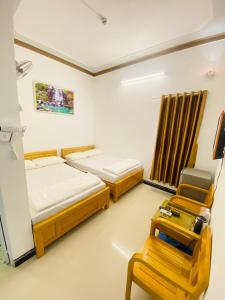 Ninh HảiにあるHotel Aloha 2のベッド2台と椅子が備わる客室です。