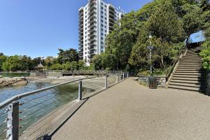 a walkway next to a river with a tall building at Victoria West Harbourview in Victoria