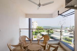 Marmagaoにある1 BHK Sunrise & Seaside Solitudeのバルコニー(テーブル、椅子付)、大きな窓が備わります。