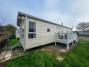 a small white house with a porch and a yard at Lovely 6 Berth Caravan In Seaside Village Of Scratby, Norfolk Ref 19124s in Scratby