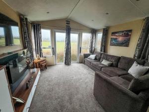 a living room with a couch and a television at Lovely 6 Berth Caravan In Seaside Village Of Scratby, Norfolk Ref 19124s in Scratby