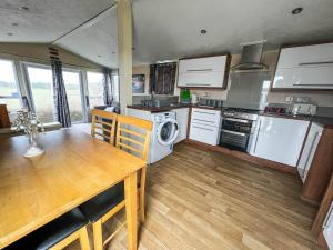 a kitchen with a table and a stove and a dishwasher at Lovely 6 Berth Caravan In Seaside Village Of Scratby, Norfolk Ref 19124s in Scratby