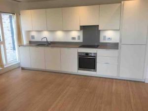 an empty kitchen with white cabinets and a sink at Luxury 2 bed ensuite 2 bathroom apartment East Croydon in South Norwood