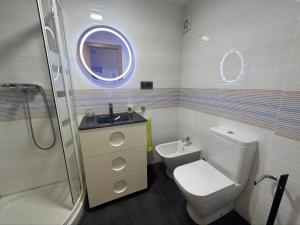 ein Badezimmer mit Toilette, Waschbecken und Spiegel in der Unterkunft Piso a pie de playa con piscina y vistas al mar in Benicàssim + 13 Fotos