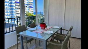 balcón con mesa, sillas y vasos. en Piso a pie de playa con piscina y vistas al mar, en Benicàssim