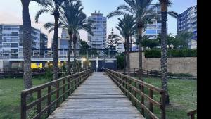 eine Holzbrücke mit Palmen und einem Zug in der Unterkunft Piso a pie de playa con piscina y vistas al mar in Benicàssim