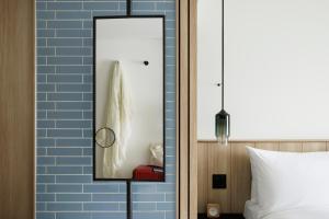 a mirror on a wall next to a bed at Fairfield by Marriott Saga Ureshino Onsen in Ureshino