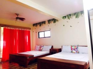 a room with two beds and red curtains at Orlando Beach Resort in Lemery