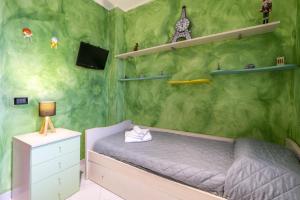 a bedroom with a green wall with a bed and shelves at Green house in Monopoli