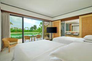 a bedroom with two beds and a view of a lake at Sheraton Belitung Resort in Tanjungbinga