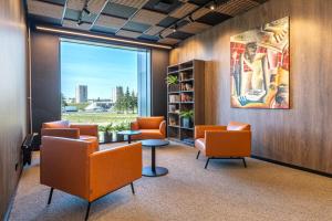 a waiting room with orange chairs and a table at Väo Keskus Modern Guest Apartments in Tallinn