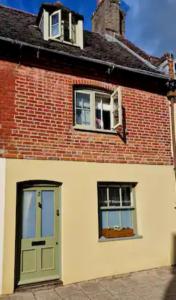 a brick building with a green door and two windows at Jackdaw Cottage-Beautiful Cottage, Town Centre in Wimborne Minster