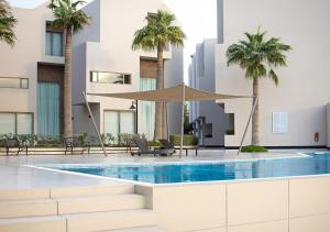 a swimming pool with palm trees in a building at SeaLoft Villas in Manama