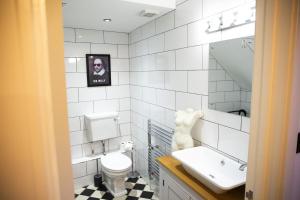 a white tiled bathroom with a toilet and a sink at The Penthouse at Mercers Croft in Stratford-upon-Avon