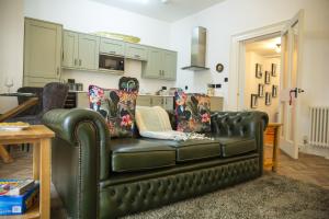 a living room with a black leather couch and a table at The Penthouse at Mercers Croft in Stratford-upon-Avon