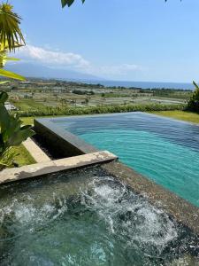 a swimming pool with blue water in a field at Bula Villa in Umeanyar