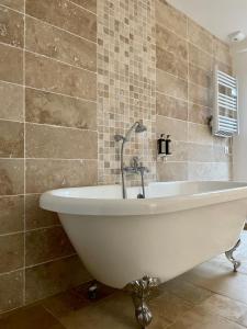 La salle de bains est pourvue d'une baignoire blanche et de carrelage. dans l'établissement Madame Imagine, Lodges & SPA Epinal, à Épinal