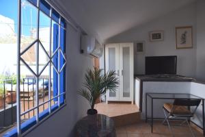 un soggiorno con TV e tavolo con una pianta di Habitación en centro histórico a Málaga