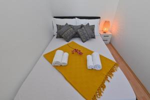 uma cama com duas almofadas brancas e um cobertor amarelo em Apartment Adela II em Novalja