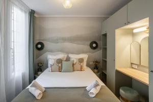 una camera da letto con letto, lenzuola e cuscini bianchi di The Liberty Green Suite a Parigi