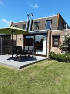 een patio met stoelen en een parasol voor een gebouw bij Heggerank 5B* in Nieuwvliet