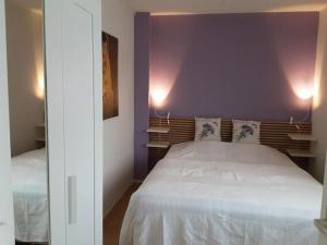 um quarto com uma cama branca e uma parede roxa em Heggerank 5B* em Nieuwvliet